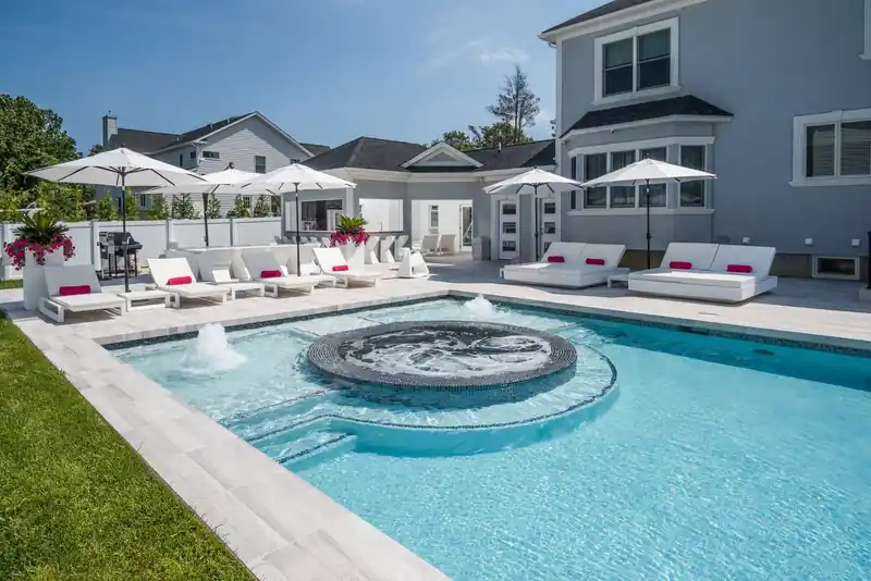 Circular spa with a fountain in front of a white house
