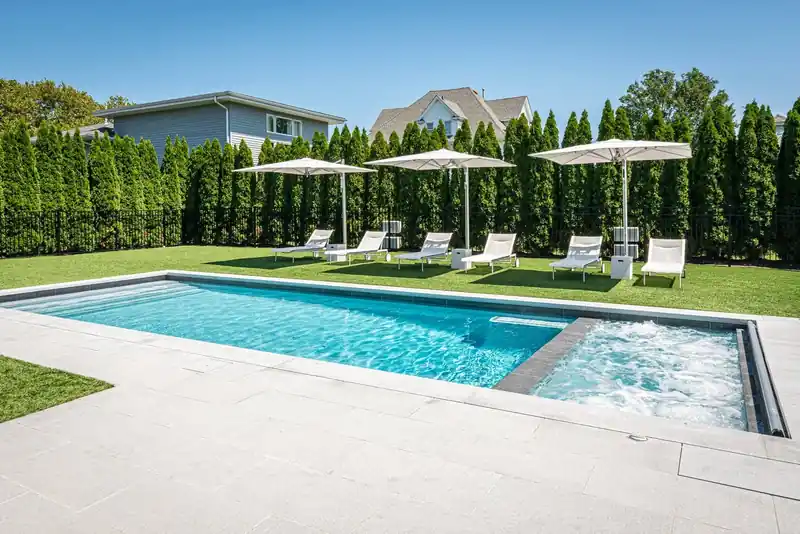 Pool framed by a tall arborvitae hedge