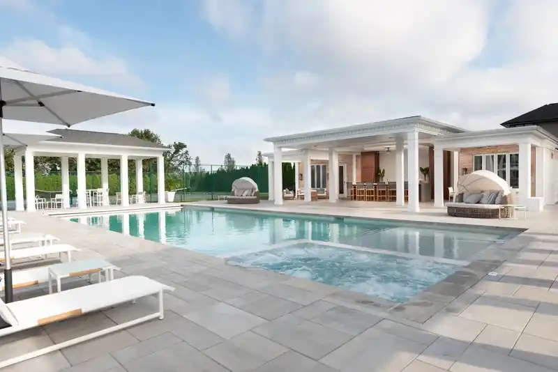 Long rectangular pool in front of a white colonnade pavilion, loungers along one side
