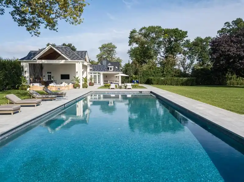 Long pool running up to a grey-shingled house