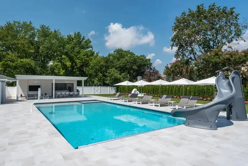 Pool with a curving slide beside a white pavilion