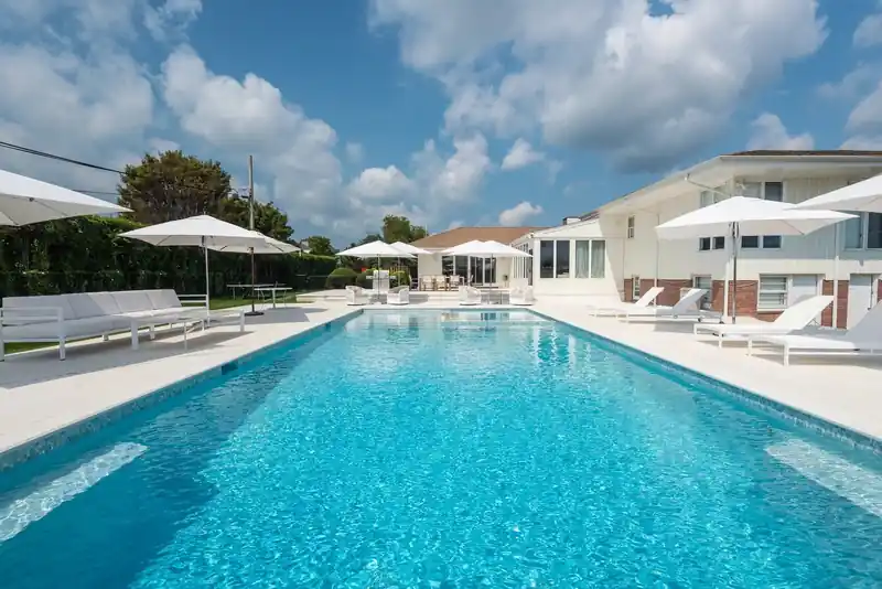 Long pool lined with white loungers and umbrellas